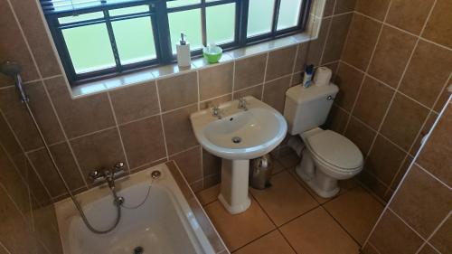 a bathroom with a sink and a toilet and a tub at The Highveld Cape Inn in Pretoria