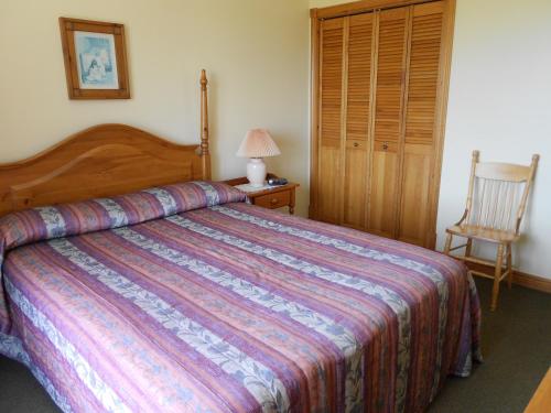 a bedroom with a large bed and a chair at Shaw's Hotel & Cottages in Brackley Beach