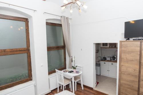 Una cocina y un comedor con una mesa y un televisor. en Raphaela Residence, en Bistriţa