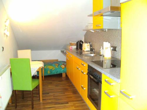 エーギングにあるHaus Kerstanのキッチン(黄色のキャビネット、テーブル、緑の椅子付)