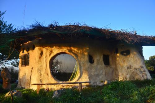 ein strohgedecktes Haus mit einem großen Fenster in der Unterkunft Hobbit House in Tandil