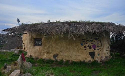 een kleine hut met een grasdak op een veld bij Hobbit House in Tandil