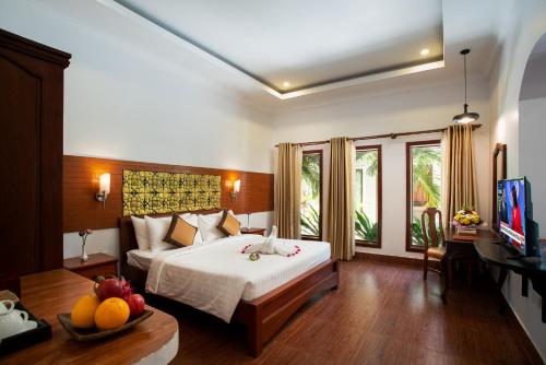 a hotel room with a bed and a television at De Arya Angkor Resort in Siem Reap