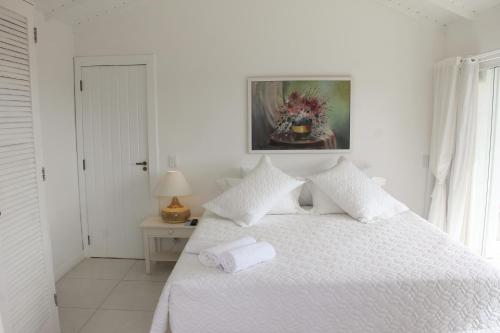 a white bedroom with a bed with a towel on it at Pousada Solar da Ferradurinha in Búzios