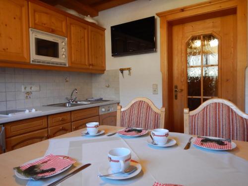 una cocina con una mesa con tazas y platillos. en Kasparbauer, en Sankt Michael im Lungau