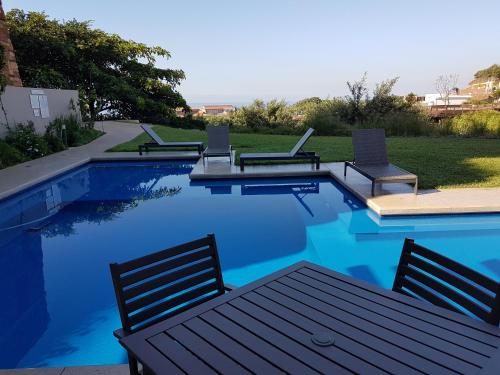 una piscina con varias sillas y una mesa. en Zimbali Suites 611, en Ballito