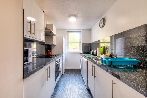 a kitchen with white cabinets and black counter tops at Charming 1 Bed Apartment with Castle View in Edinburgh
