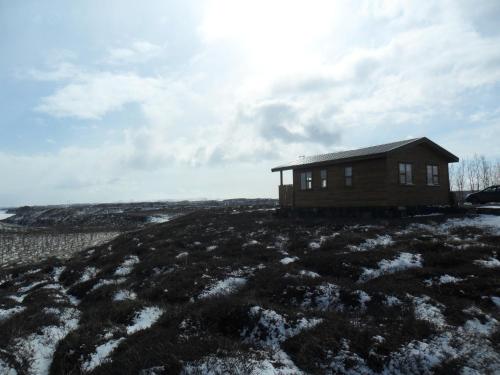 a small house on top of a hill with snow at Ekra Cottages in Lagarfljótsvirkjun