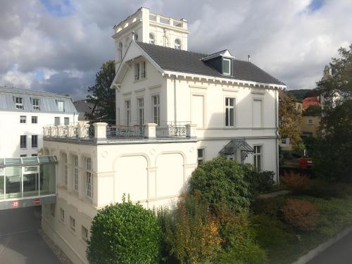 a white building with a clock tower on top of it at Hotel the YARD Bad Honnef in Bad Honnef am Rhein