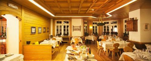 uma sala de jantar com mesas e cadeiras brancas e uma mesa de trabalho em Hotel Costabella em Passo San Pellegrino