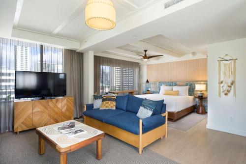 a hotel room with a bed and a blue couch at The Surfjack Hotel & Swim Club in Honolulu