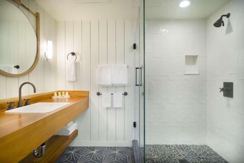 a bathroom with a shower and a sink and a glass shower door at The Surfjack Hotel & Swim Club in Honolulu