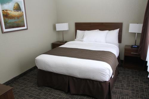 a hotel room with a large bed and two lamps at Days Inn & Suites by Wyndham Yorkton in Yorkton