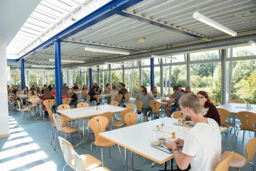 a group of people sitting at tables in a room with windows at Jugendherberge Hannover in Hannover