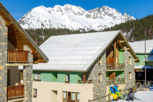 a ski lodge with snow covered mountains in the background at Résidence Capfun Couleurs Soleil, Oz en Oisans in Oz
