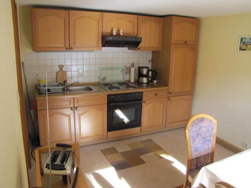 a kitchen with wooden cabinets and a stove top oven at Ferienwohnung Schade in Hohnstein