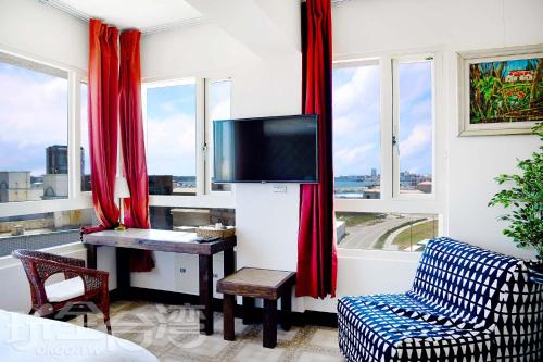 馬公市的住宿－Blue Hole Guesthouse藍洞民宿，客厅配有书桌、电视和窗户。