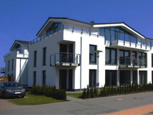 a white building with a car parked in front of it at Haus Calmsailing in Börgerende-Rethwisch