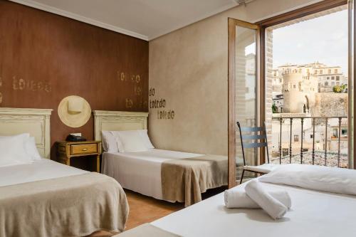 um quarto de hotel com duas camas e uma varanda em YIT Puerta Bisagra em Toledo