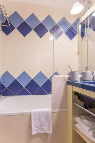 La salle de bains est revêtue de carrelage bleu et blanc. dans l'établissement Résidence Pierre & Vacances La Baie des Sables, à Les Sables-dʼOlonne