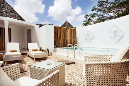 an outdoor patio with wicker chairs and a tub at Gold Zanzibar Beach House & Spa in Kendwa