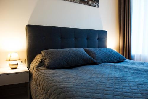 - une chambre avec un lit bleu et une grande tête de lit dans l'établissement Apartment4Me, à Palanga
