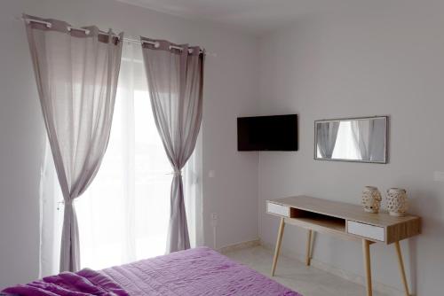 a bedroom with a bed and a desk with a mirror at Paulsia Apartments in Psinthos