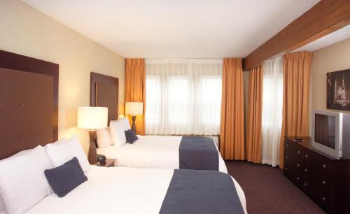 a hotel room with two beds and a television at Ivy Court Inn and Suites in South Bend