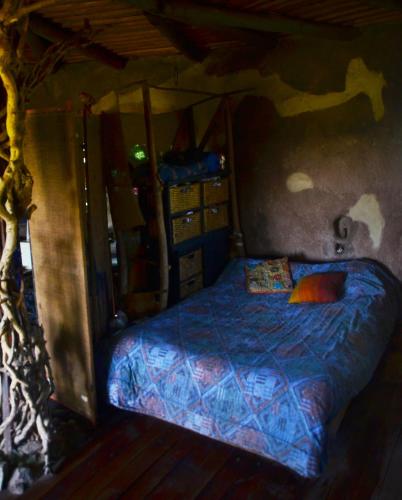 een slaapkamer met een bed met een blauw dekbed bij Hobbit House in Tandil