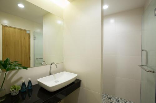 a white bathroom with a sink and a shower at DeeProm Pattaya Hotel in Pattaya Central