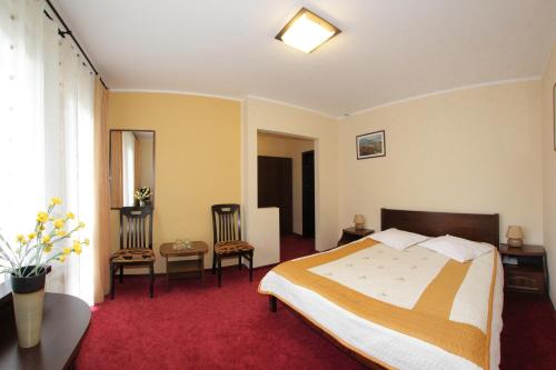 a hotel room with a bed and two chairs at Hotel Victoria in Borşa