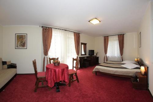 a bedroom with a bed and a table with a red carpet at Hotel Victoria in Borşa