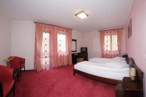 a bedroom with a large bed and two windows at Hotel Victoria in Borşa