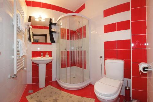 a red and white bathroom with a toilet and a shower at Hotel Victoria in Borşa