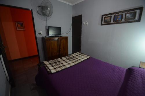 a bedroom with a purple bed and a tv at Hostal Namaste in Salta