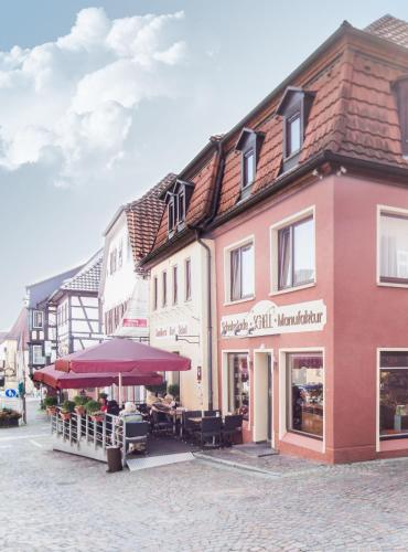 a building with tables and umbrellas on a street at Schell Schokoladen in Gundelsheim