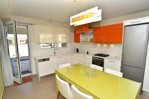 a kitchen with a yellow table and a refrigerator at The Villa of the Winds in Néa Kíos