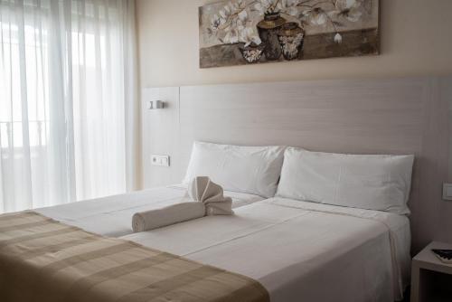 Una cama blanca con un arco encima. en Apartamentos Massò en Albacete