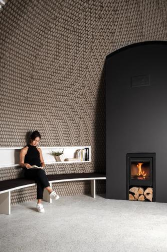 a woman sitting on a bench in front of a fireplace at Casa de São Lourenço - Burel Panorama Hotel - member of Design Hotels in Manteigas