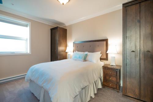 Un dormitorio con una gran cama blanca y una ventana en SookePoint Ocean Cottage Resort en Sooke