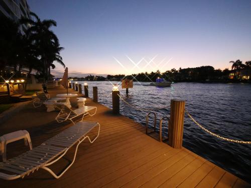 a dock with chairs and tables and a boat on the water at Holiday Isle Yacht Club in Fort Lauderdale