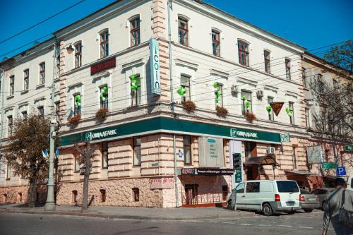 ein großes weißes Gebäude mit grünen Schildern darauf in der Unterkunft Coin Apartments & Poshtel in Czernowitz