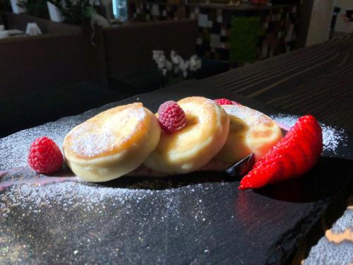 two d pancakes with strawberries on a black plate at Coin Apartments & Poshtel in Chernivtsi