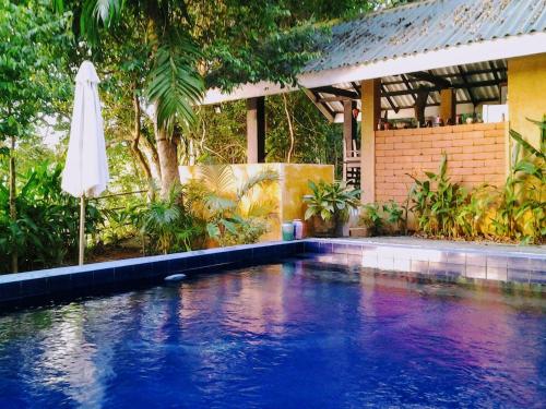 a swimming pool with a white umbrella and a house at Randoni Villa in Raddoluwa