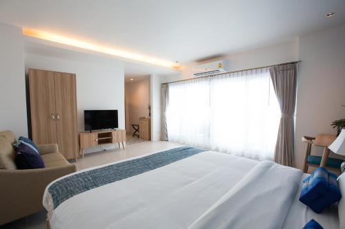 a hotel room with a large bed and a television at DeeProm Pattaya Hotel in Pattaya Central