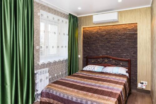 a bedroom with a bed with a green curtain at Apartment na Respubliki in Tyumen