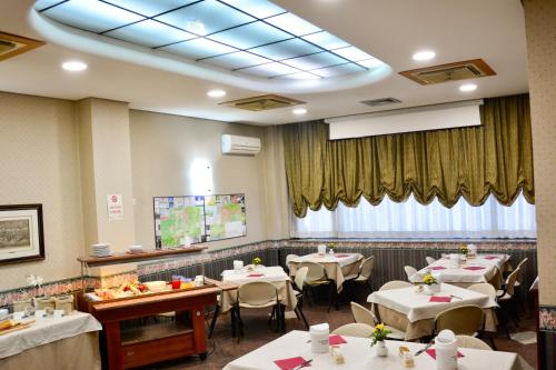 a restaurant with white tables and chairs and a large window at Hotel Kroma in Ragusa