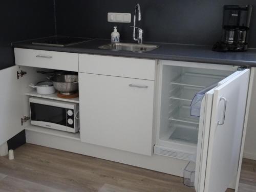a white kitchen with a sink and a microwave at Het Bakkersschuurtje in Colijnsplaat