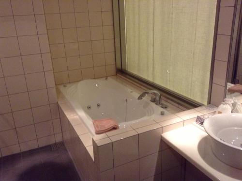 a bathroom with a bath tub and a sink at Furano Hotel in Furano