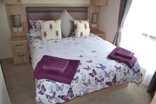 a bedroom with a large bed with purple blankets and pillows at The Balmoral Caravan in Dornoch